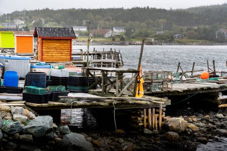 Téléchargez les photos : Des hangars de pêche colorés et des quais le long d'une plage rocheuse sur la côte est du Canada à Heart's Content Terre-Neuve sous un ciel orageux. - en image libre de droit