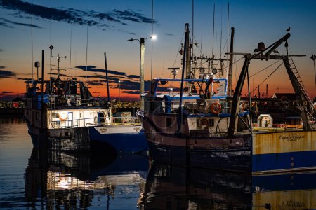 Photo for Bonavista Newfoundland Canada, September 23 2022: Evening fishing vessels moored at a dock under sunset sky. - Royalty Free Image