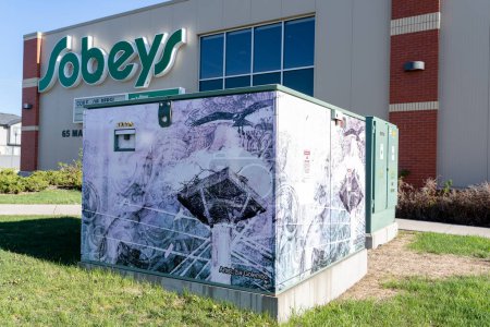 Foto de Airdrie Alberta Canada, 27 de julio de 2022: Una caja eléctrica decorada como una exhibición de arte público junto a una tienda de comestibles. - Imagen libre de derechos