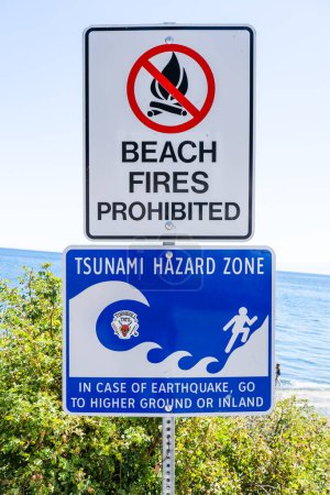 Téléchargez les photos : Victoria Colombie-Britannique Canada, 15 juillet 2023 : Panneau d'avertissement de tsunami et d'interdiction de feu de plage à un point de départ de sentier menant à Taylor Beach Metchosin. - en image libre de droit