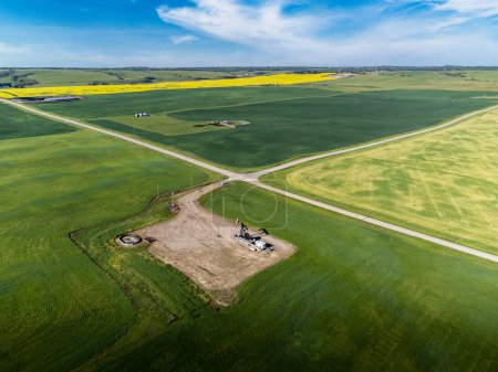 Photo for Aerial oil and gas well at crossroads overlooking agriculture fields on the Canadian prairies in Alberta Canada. - Royalty Free Image