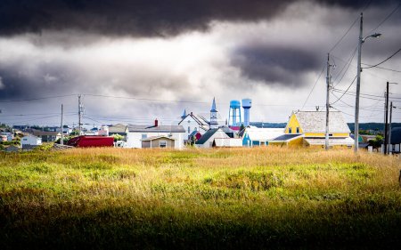 Photo for Bonavista Newfoundland Canada, September 21 2022: East Coast town with historic memorial church and water towers overlooking power lines and an empty field under a stormy sky. - Royalty Free Image
