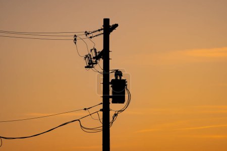 Foto de Silueta de polo de potencia con resistencias y transformadores en una red eléctrica bajo el cielo del atardecer en Alberta Canadá. - Imagen libre de derechos