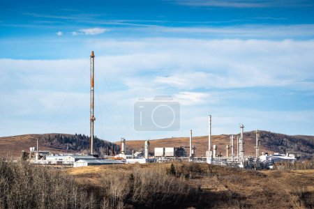 Téléchargez les photos : Usine à gaz avec cheminée et équipement industriel surplombant les contreforts près de Cochrane Alberta Canada. - en image libre de droit