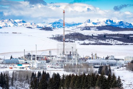 Téléchargez les photos : Rocky View County Alberta Canada, 24 janvier 2024 : Usine à gaz avec cheminée surplombant les montagnes Rocheuses canadiennes près de Cochrane Alberta. - en image libre de droit