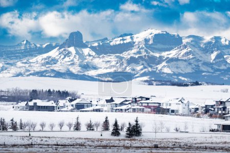 Foto de Nueva comunidad de Armonía con vistas a los campos agrícolas y las montañas rocosas canadienses al oeste de la ciudad de Calgary durante el invierno. - Imagen libre de derechos