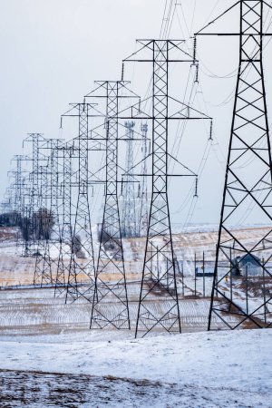 Strommasten Porträtansicht mit Stromleitungen mit Blick auf landwirtschaftliche Felder im ländlichen Alberta Kanada.