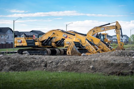 Photo for Airdrie Alberta Canada, May 18 2024: Row of excavators parked ready to begin construction at a new residential home development construction site. - Royalty Free Image