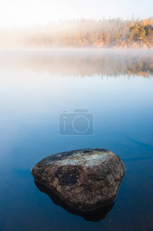 Lago inmóvil con rocas al amanecer