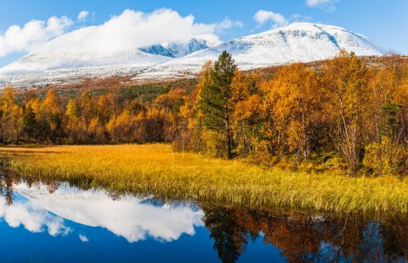 Téléchargez les photos : Couleurs d'automne à côté du petit lac devant les montagnes enneigées - en image libre de droit