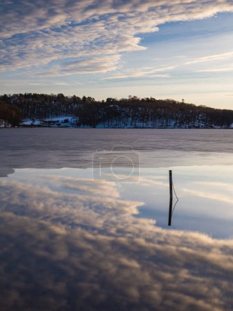 Téléchargez les photos : Un paysage hivernal paisible en Suède, reflétant un ciel matinal de nuages et de neige tranquilles. Un beau miroir de la beauté des natures. - en image libre de droit