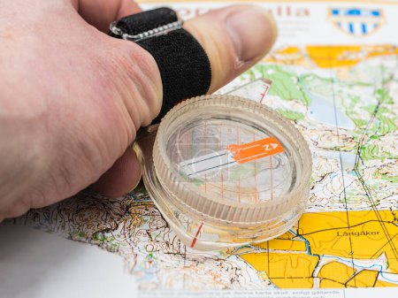 Photo for Hand holding a compass on an orienteering map - Royalty Free Image