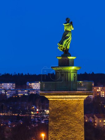 Photo for Illuminated by night, a bronze statue of a woman stands at the Gothenburg waterfront as an iconic tribute for the people at home and for their thoughts and prayers. - Royalty Free Image