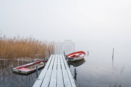 Téléchargez les photos : Bateaux à jetée givrée dans un lac brumeux - en image libre de droit