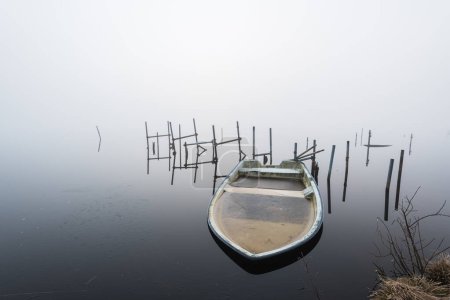 Photo for Boat filled with ice in a misty lake - Royalty Free Image