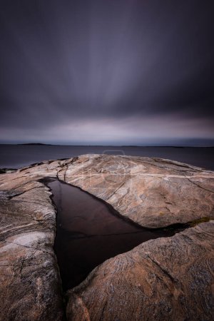 Téléchargez les photos : Gros plan de roche avec ciel dramatique et mer calme - en image libre de droit