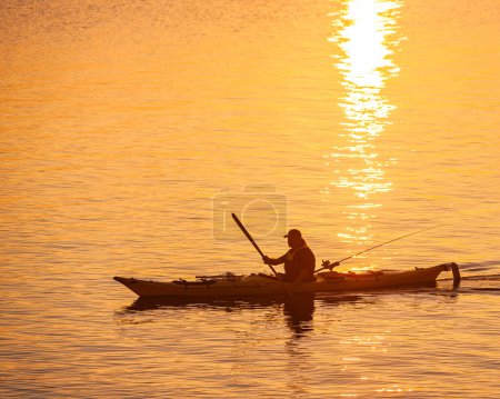 Photo for VANERN, SWEDEN - JULY 18, 2011: Silhouette of man fishing in kayak. - Royalty Free Image