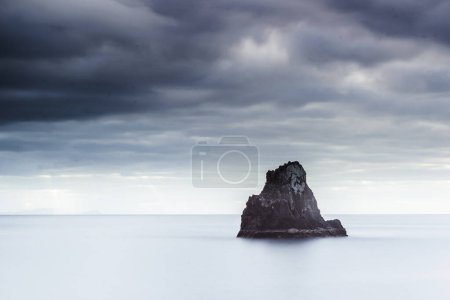 Photo for A dramatic sky hangs over the tranquil sea stack, inspiring peace and awe at the beauty of nature on Madeiras rugged coastline. - Royalty Free Image