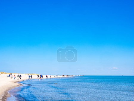 Foto de SKAGEN, DINAMARCA - 20 DE MAYO DE 2023: Un día de verano perfecto en la playa: un gran grupo de personas disfrutando de la belleza y la serenidad de la naturaleza, con un cielo sin fin que se encuentra con vastas aguas azules del océano. - Imagen libre de derechos
