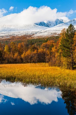 Foto de Colores otoñales además de un pequeño lago frente a montañas cubiertas de nieve - Imagen libre de derechos