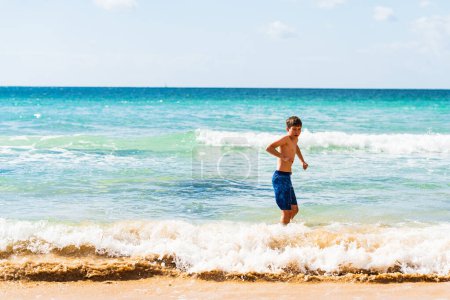 Téléchargez les photos : Garçon en maillot de bain bleu debout au bord de l'eau, Alvor, Algarve, Portugal, Europe - en image libre de droit