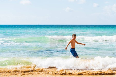 Téléchargez les photos : Garçon jouant au bord de l'eau en short bleu, Alvor, Algarve, Portugal, Europe - en image libre de droit