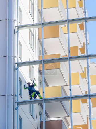 Foto de GOTHENBURG, SUECIA - 9 de mayo de 2022: Limpiador de ventanas colgado de cuerdas contra un edificio - Imagen libre de derechos