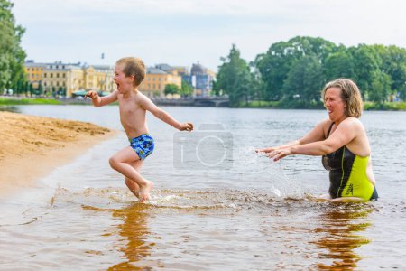 Téléchargez les photos : Mère et jeune garçon jouant dans l'eau - en image libre de droit