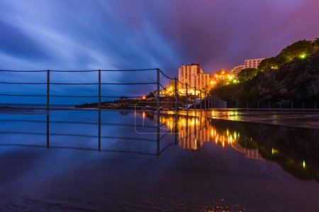 Foto de Reflexión de barandilla sobre muelle frente a edificios costeros - Imagen libre de derechos