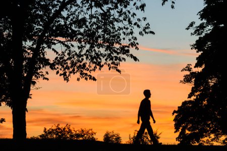 Téléchargez les photos : Silhouette de l'homme marchant au coucher du soleil - en image libre de droit