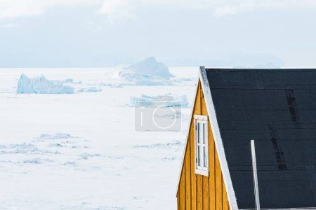 Foto de Casa amarilla frente al mar congelado - Imagen libre de derechos