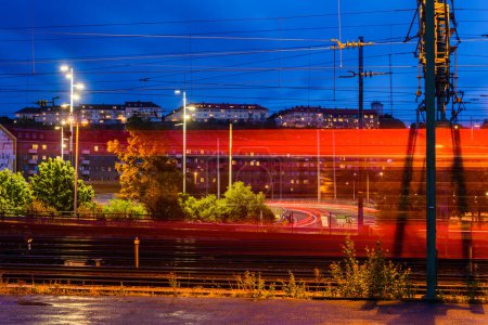 Téléchargez les photos : Train passant en ville le soir - en image libre de droit