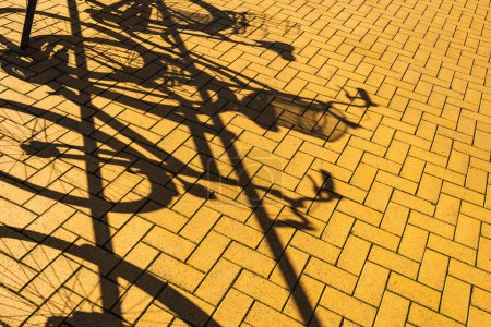 Téléchargez les photos : Vélos garés dans la rue avec des ombres - en image libre de droit