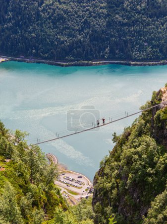 Téléchargez les photos : Aventure norvégienne : Deux personnes traversent un pont, entourées par la beauté de la nature. - en image libre de droit