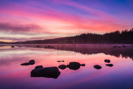 Photo for Tranquil sunrise over a serene Swedish lake with pink sky. - Royalty Free Image