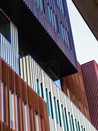 Foto de Esta imagen destaca el llamativo detalle de un exterior de edificios contemporáneos con una combinación de coloridas persianas verticales. La foto captura el contraste entre los elementos de diseño únicos de los edificios y el cielo despejado, posiblemente tomado en un - Imagen libre de derechos