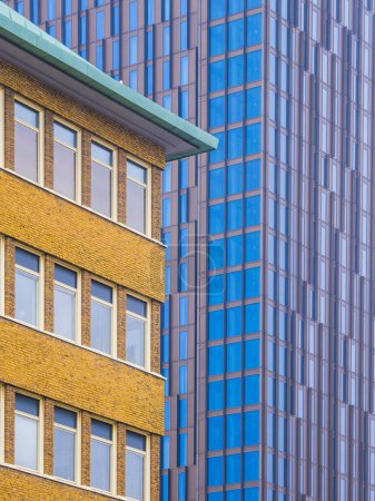 Das Foto fängt das Nebeneinander zweier unterschiedlicher Gebäude im schwedischen Göteborg ein. Im Vordergrund steht eine traditionelle Backsteinfassade mit sichtbaren Fenstern und einer markanten Dachlinie vor dem Hintergrund eines modernen Glashochhauses mit,