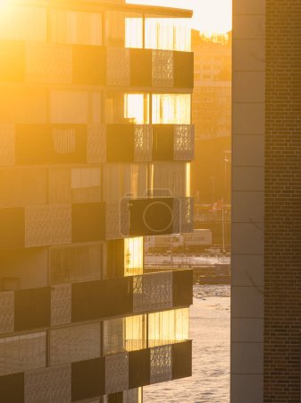 Ein Wohnhaus, das während des Sonnenaufgangs in Göteborg, Schweden, neben einem Gewässer steht. Die Spiegelung des Gebäudes spiegelt sich im ruhigen Wasser.