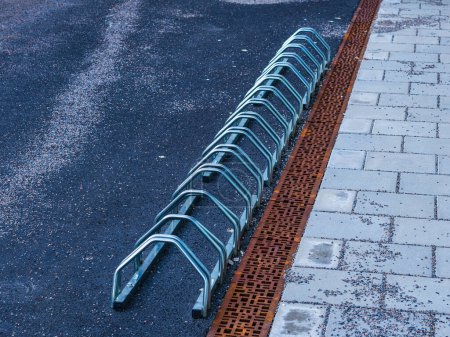 A Metal Bike Rack on the side of a road, waiting for weary cyclists.