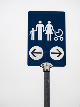 A blue and white sign displays symbols representing a family, including an adult, child, and a stroller, with arrows pointing in opposite directions against a clear background.