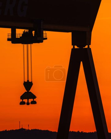 Silhouetted Crane at a Swedish Wharf Against a Vibrant Sunrise Sky