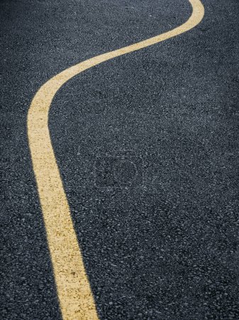 Eine Straße in Schweden mit einer lebhaften gelben geschwungenen Linie, die durch das Zentrum führt und Fahrzeuge über das glatte Pflaster lenkt.