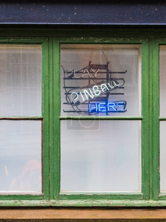 Téléchargez les photos : Un panneau sur le côté d'un bâtiment à Gothenburg, en Suède, annonçant la possibilité de jouer au flipper à l'intérieur. Le panneau est affiché bien en vue près d'une fenêtre, invitant les passants à entrer et à profiter du jeu. - en image libre de droit