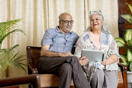 Photo for Happy Indian Grey hair Senior couple sitting at sofa in Living room and enjoying life - Royalty Free Image