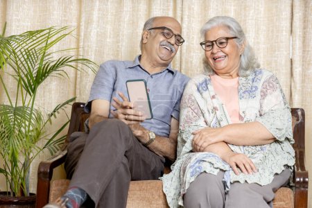 Photo for Indian senior couple Sitting on sofa at living room and using phone , Retired life concept - Royalty Free Image