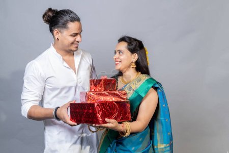 Téléchargez les photos : Portrait sur heureux jeune couple indien tenant boîte cadeau se regardant, concept d'offre festive Diwali - en image libre de droit