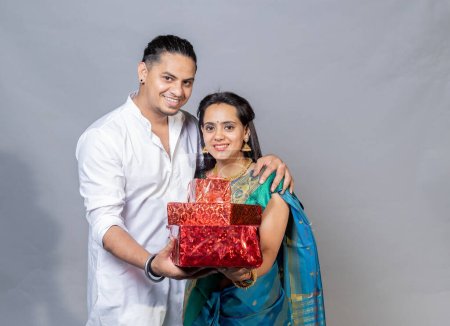 Téléchargez les photos : Portrait sur heureux jeune couple indien tenant boîte cadeau regardant vers l'appareil photo, concept d'offre festive Diwali - en image libre de droit