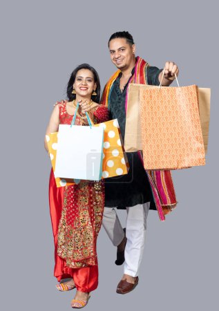 Photo for Happy indian couple wearing traditional cloths holding shopping bags and celebration diwali festival together - Royalty Free Image