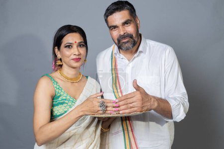 Photo for Indian couple in ethnic wear with prayer plate looking towards the camera,Indian couple in ethnic wear celebrating Festival,diwali - Royalty Free Image
