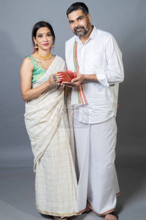 Téléchargez les photos : Portrait sur le couple sud-indien ouvrant boîte cadeau regardant vers la caméra - en image libre de droit